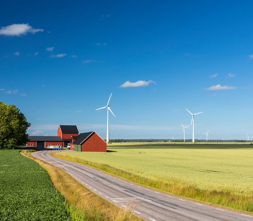 In the province of Dasland in Sweden, a few wind turbines surround a traditional red Swedish farmhouse in a yellow wheat fields. The panoramic view is composed of colorful colors, the yellow wheat, a clear blue sky and a red farmhouse. With the wind turbines, the image also displays the modern high technology used for the environmental protection of the nature and the traditional farming.